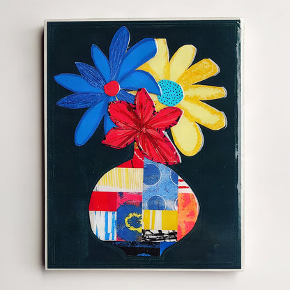 A colorful abstract floral painting on a dark background, featuring blue, yellow, and red flower-like shapes emerging from a patchwork-patterned vase, shown against a light wall.