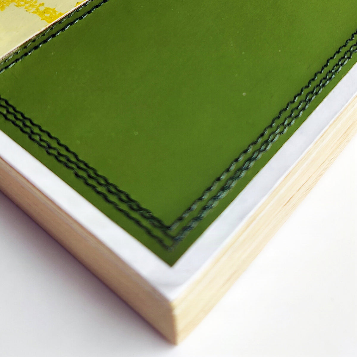 Close-up view of machine stitching along edge of wood panel