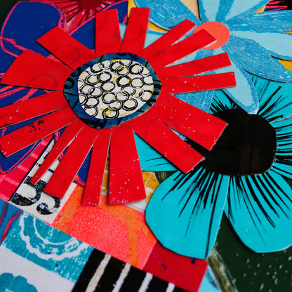 A close-up of a colorful abstract floral collage with layered cut-paper flowers in red, turquoise, black, blue.